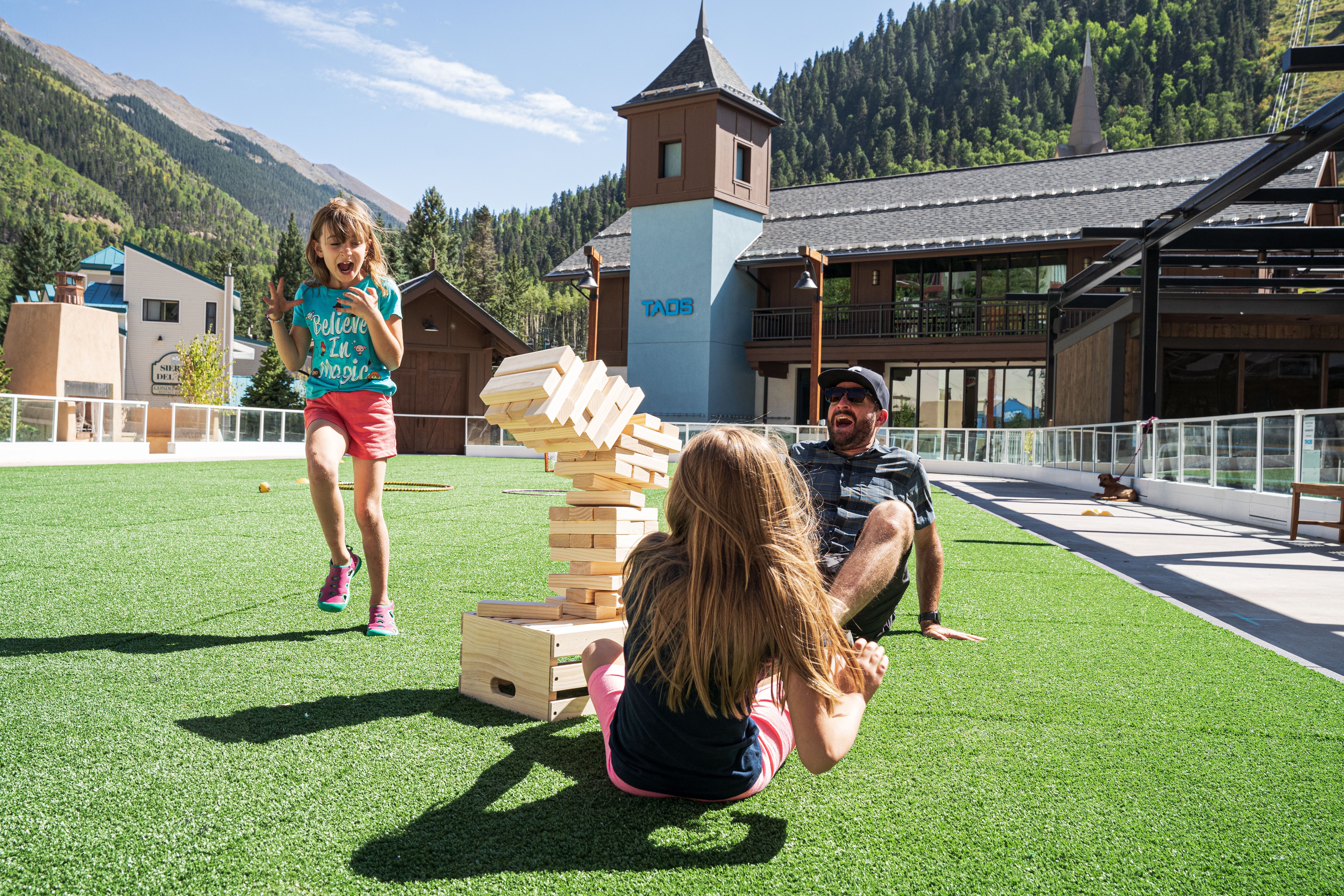 Family plays jenga on the Eis Haus turf lawn.