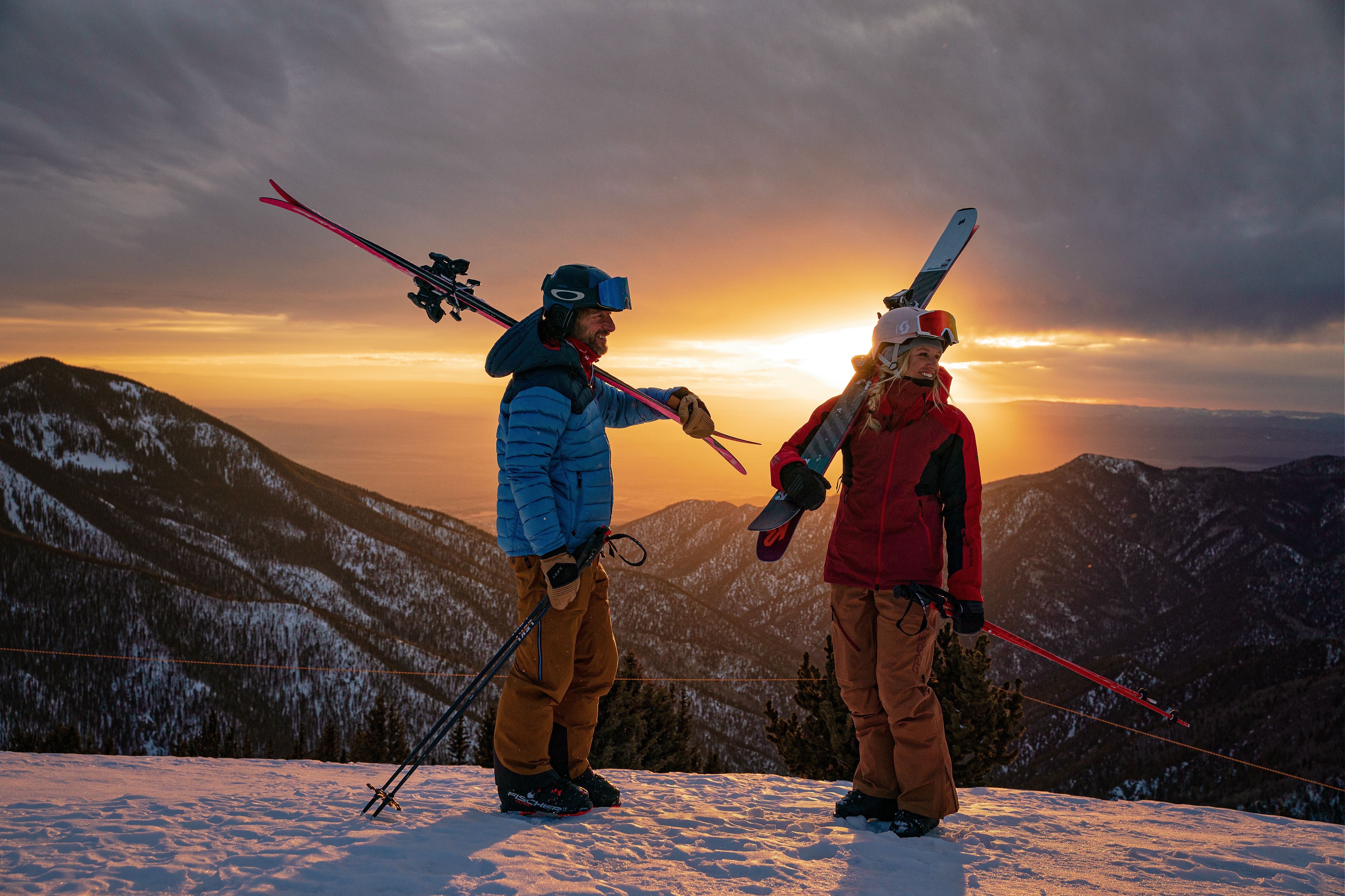 Two skiers on the ridge at Taos Ski Valley during sunset