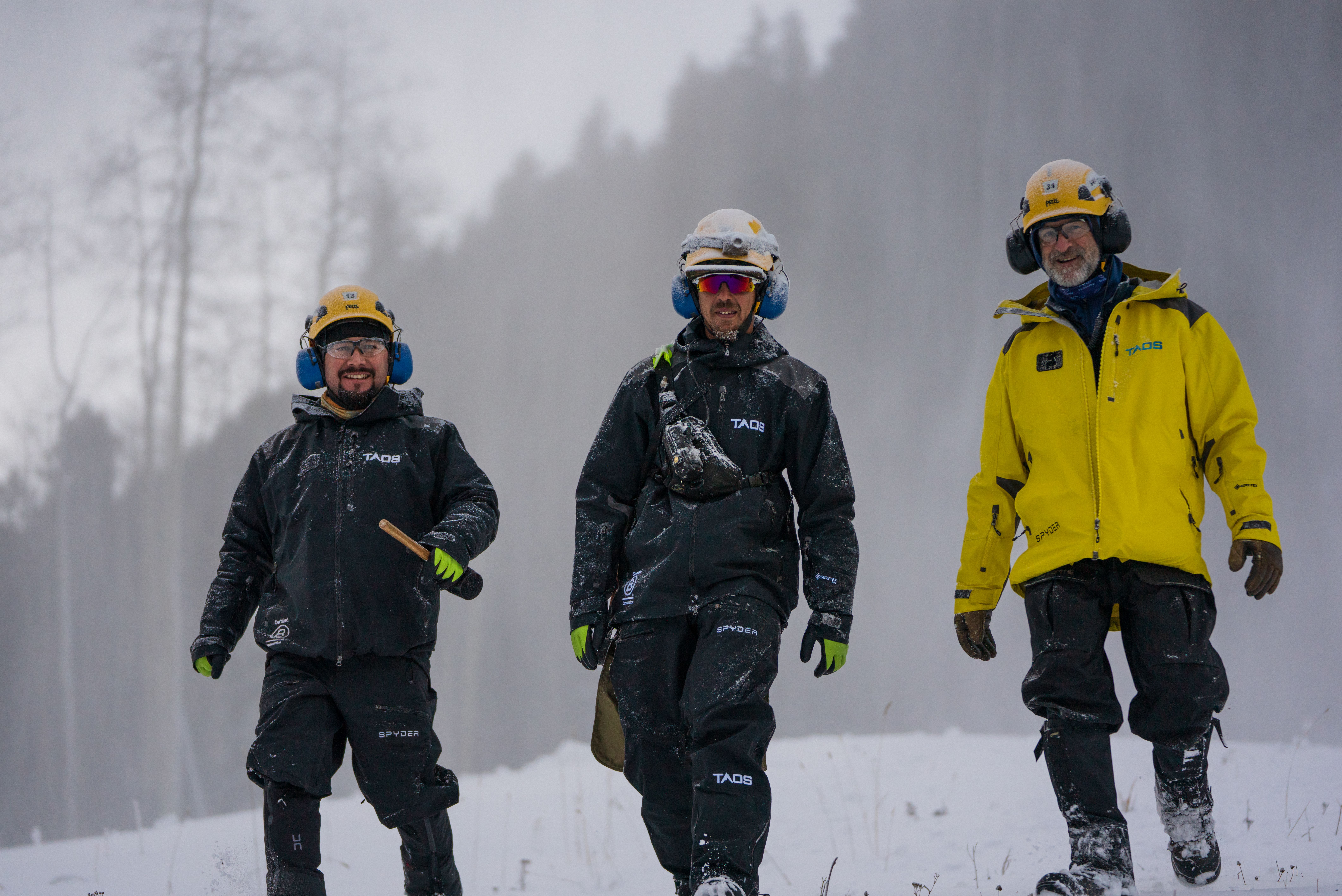 Three Taos Ski Valley employees walk down a snowy path.